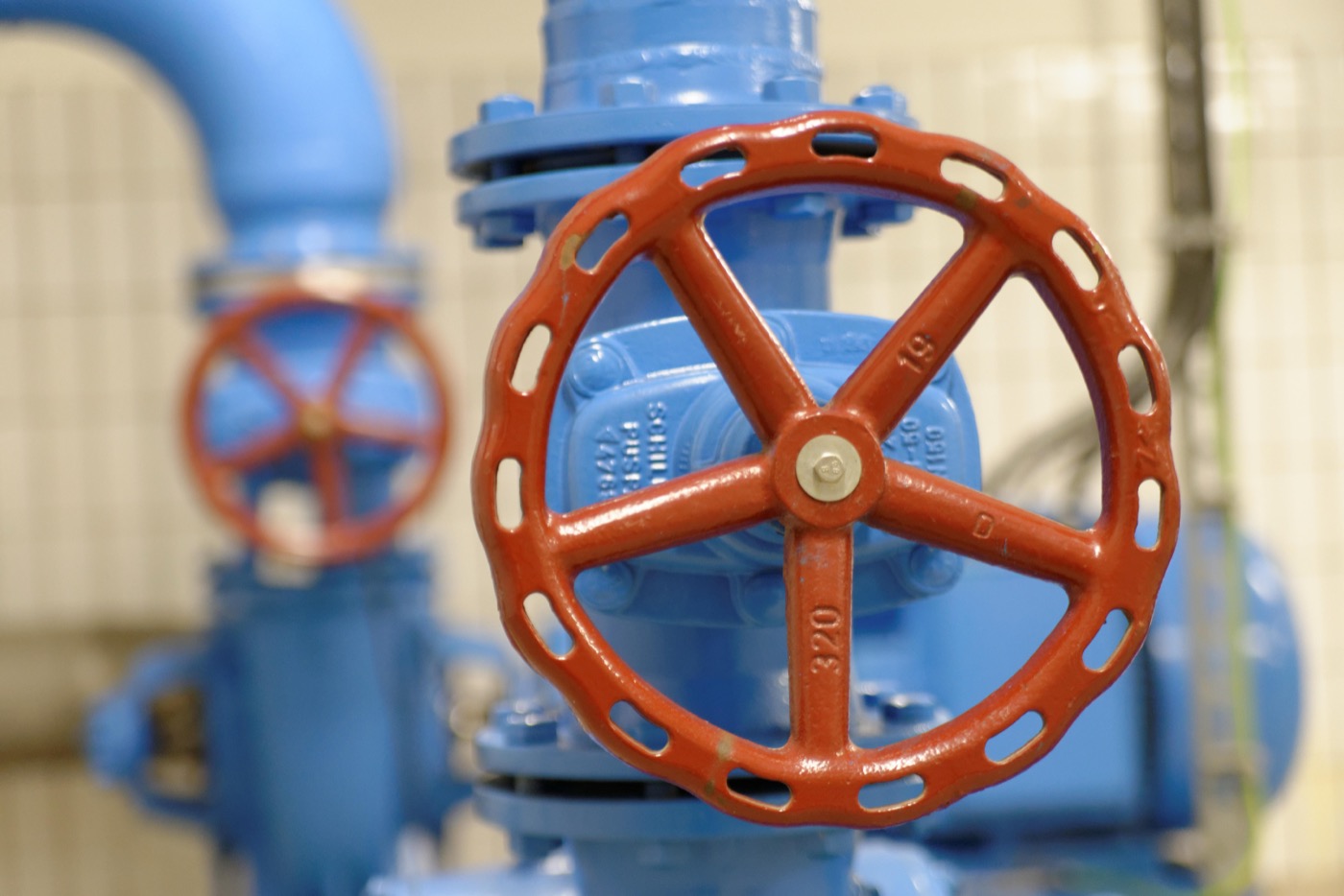 Blaue Trinkwasserrohre und ein großes rotes Rad um den Durchfluss zu steuern.